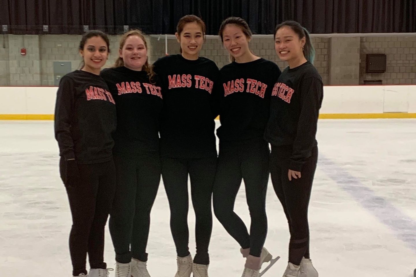 Five figure skaters posing mid-ice